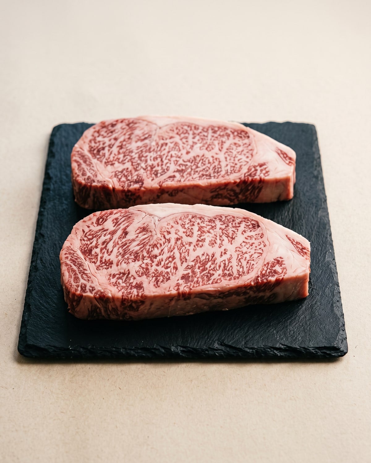 Two finely marbled Iga beef sirloin steaks resting on black slate